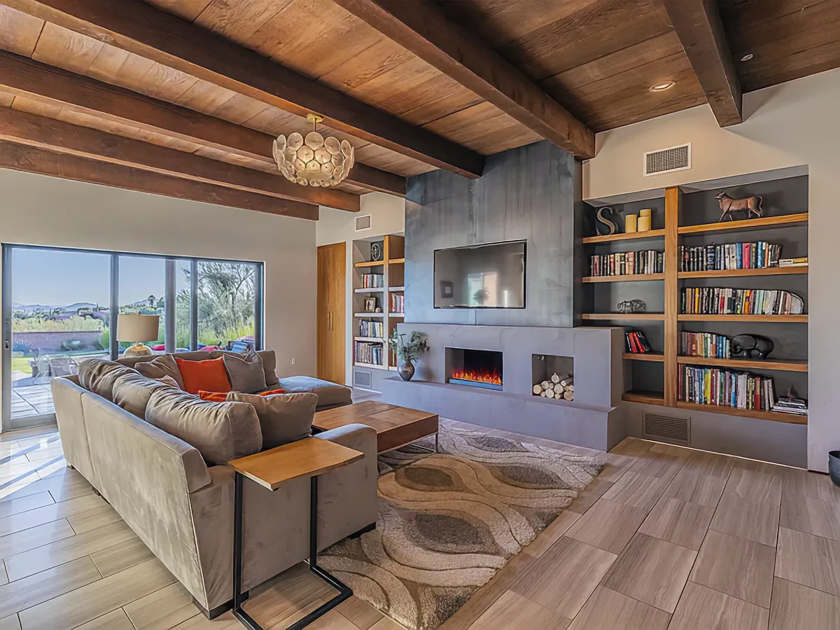 Living room at Camino Antonio with a concrete fireplace, built-in shelving and sliding doors to the patio