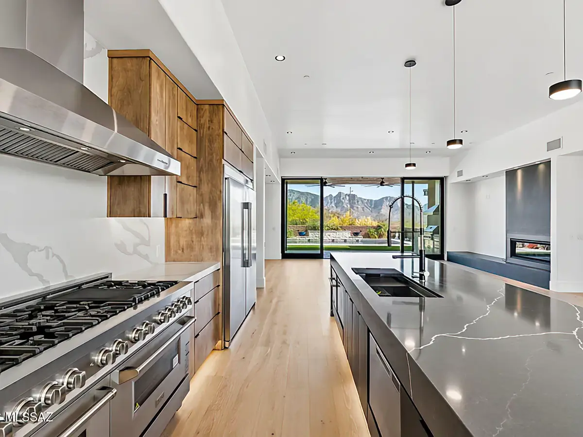 Kitchen island at The Estates at Honey Bee Ridge with waterfall-edge stone and a view down the hall to the mountains beyond