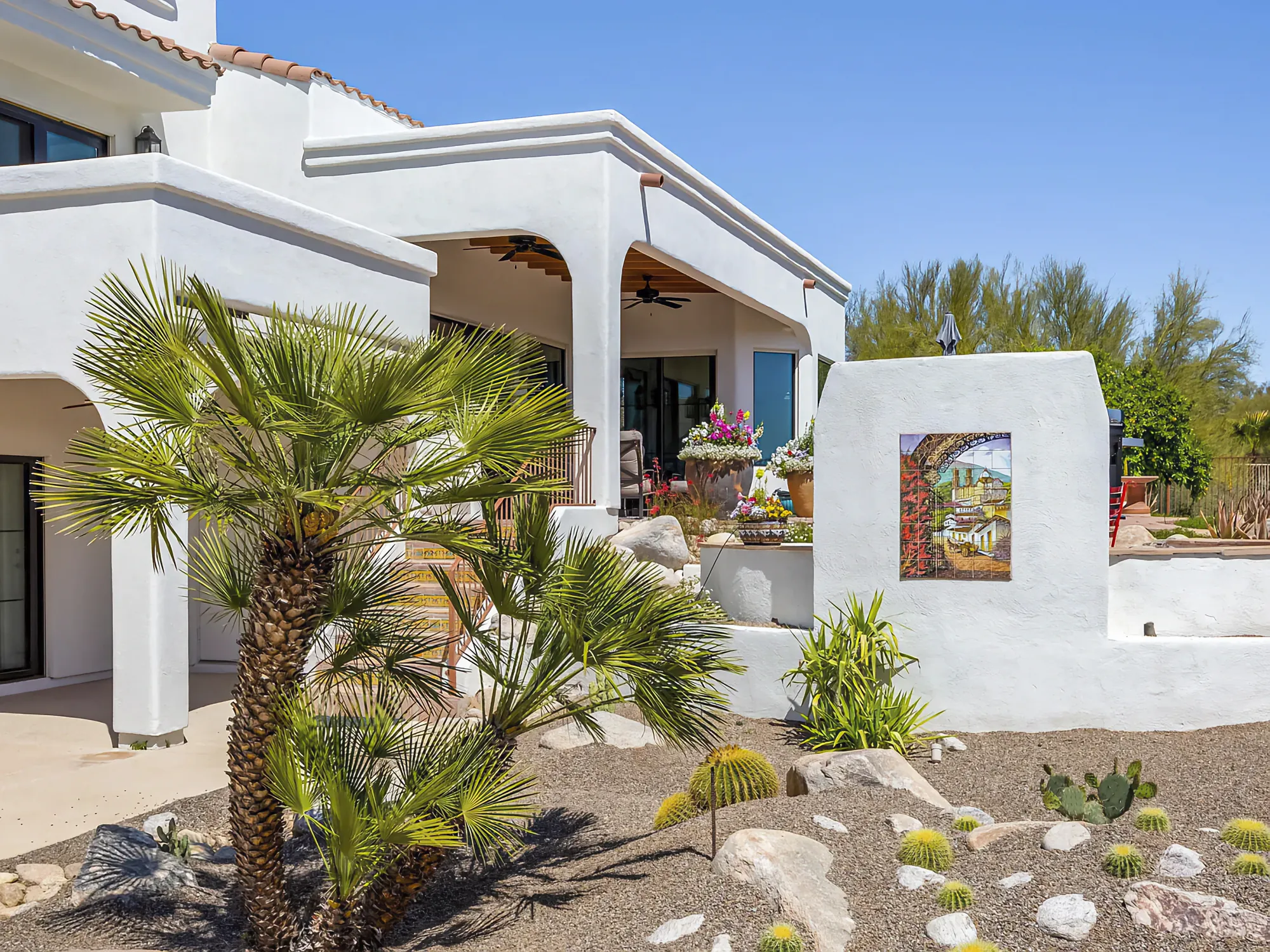Renovated Santa Fe style home at Omni Tucson National, with desert planting and a mature palm at the entry